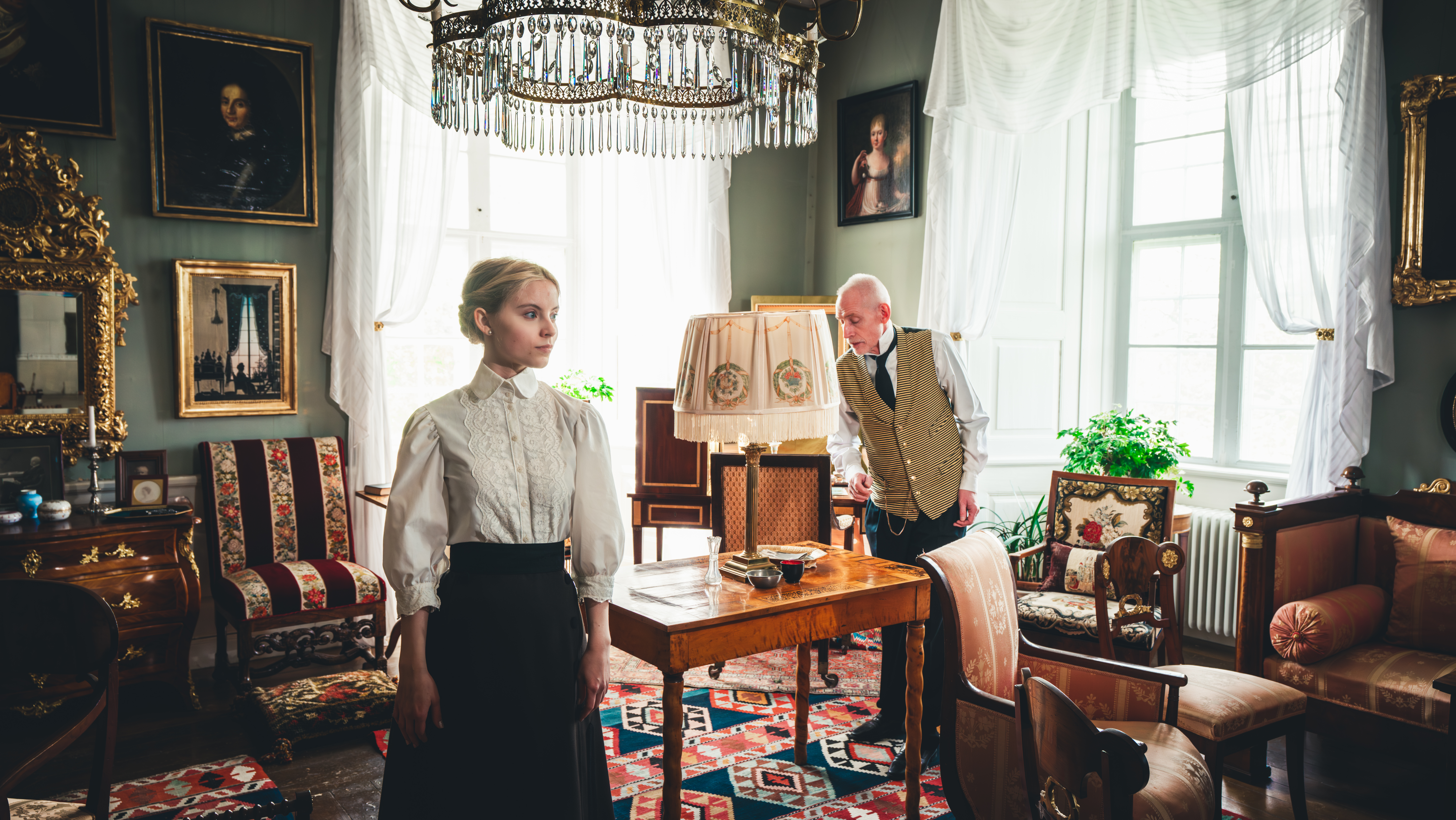 Statister i tidsenliga kläder i fröken Emilies privata vardagsrum på Löfstad slott.